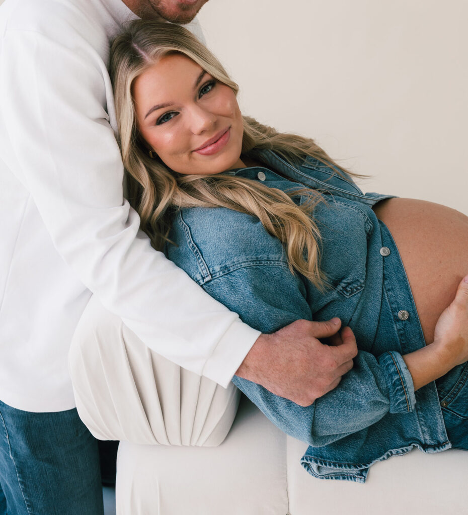 A mom who is posing with her husband for maternity photos.